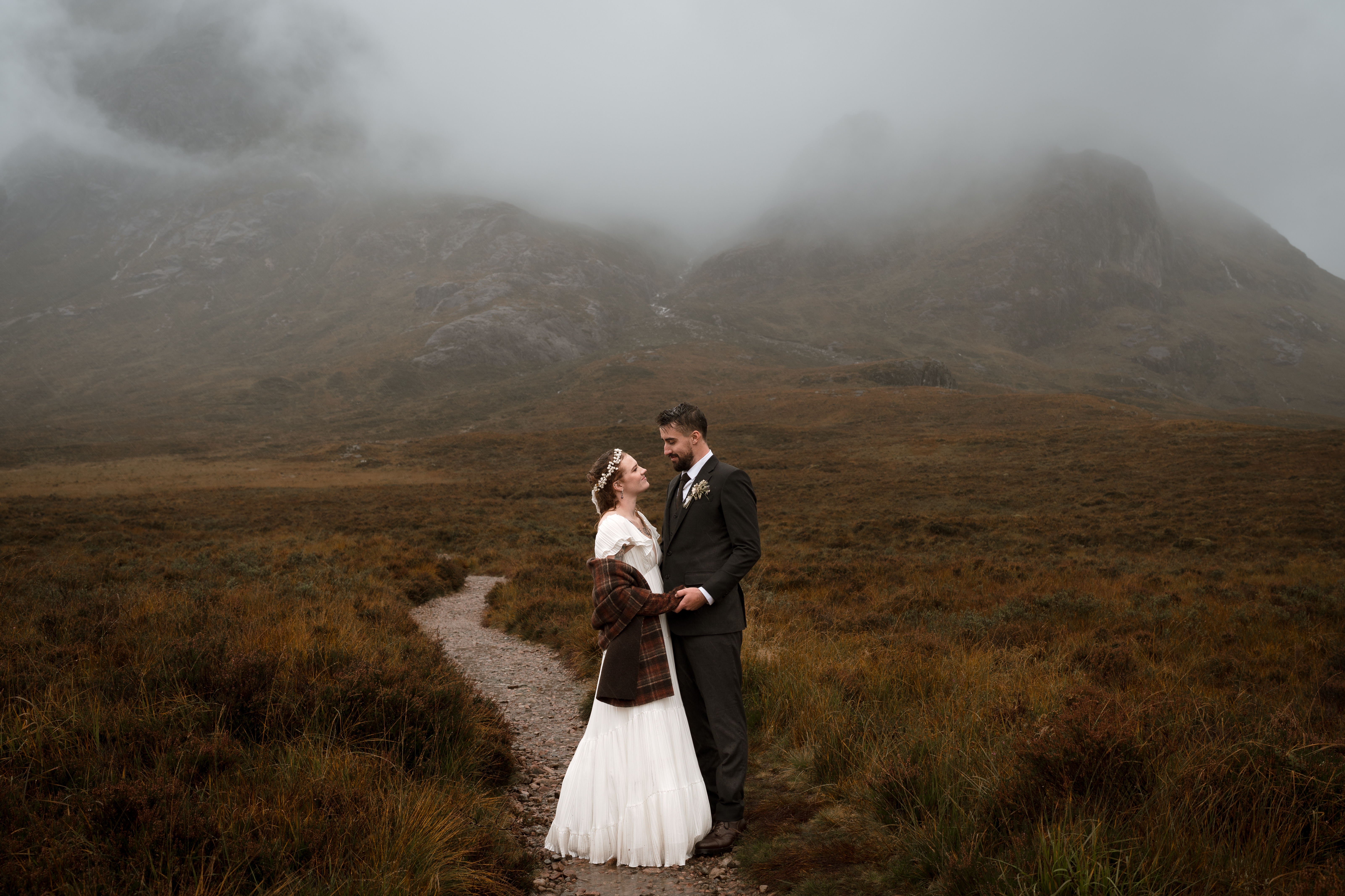 A couple walking along a Scottish beach at sunset